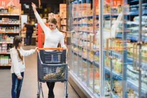 Family shopping in Australian supermarket: young mum with children choosing groceries, diverse products on shelves