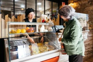 Senior woman buying takeaway food at a counter in Australia, focusing on customer service and convenience.